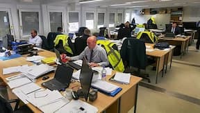 Site managers in the site office working at their desks