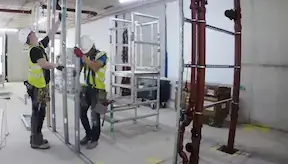 Two dryliners fixers installing the 1st fix 70mm stud wall in construction site