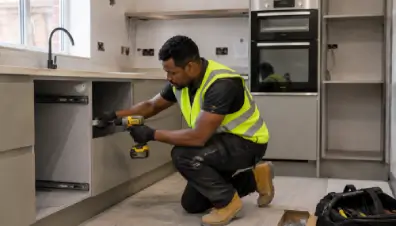 Kitchen fitter installing base and wall units during NVQ Level 2 assessment